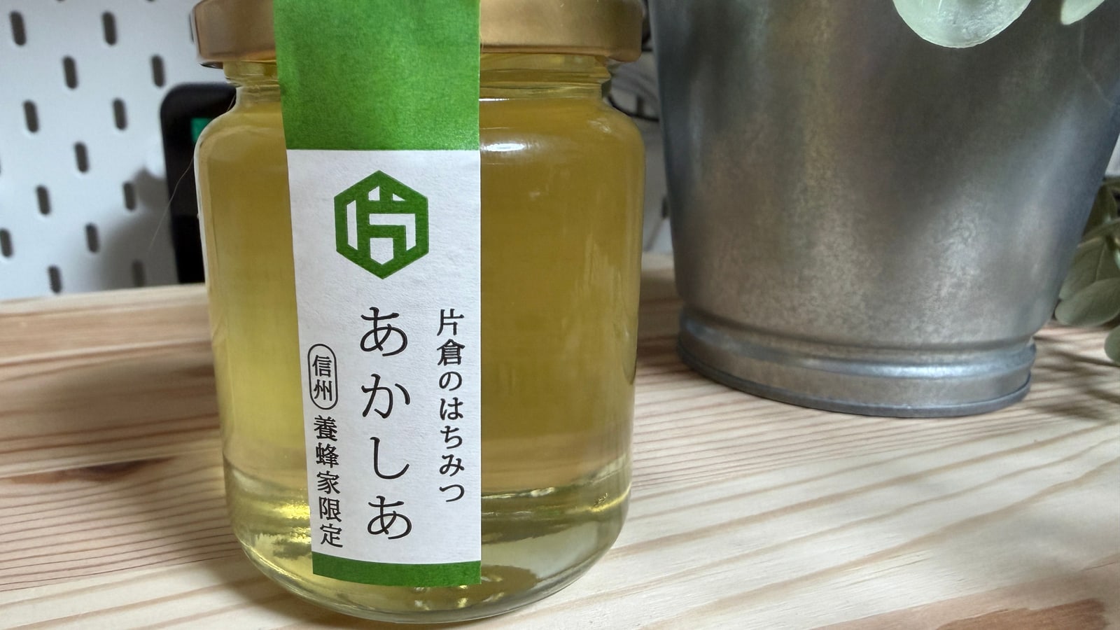 木の棚に置いた片倉養蜂場のあかしあ蜂蜜の瓶